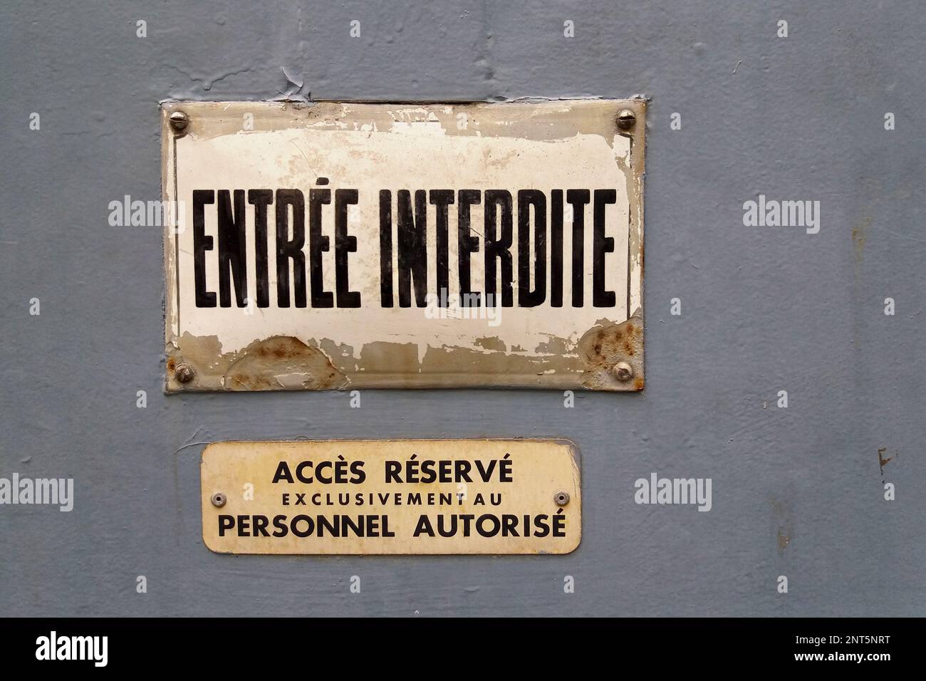 Deux panneaux sur une porte avec l'inscription française « entrée interdite » (entrée interdite) sur la première et « accès refusé au personnel autorisé » Banque D'Images
