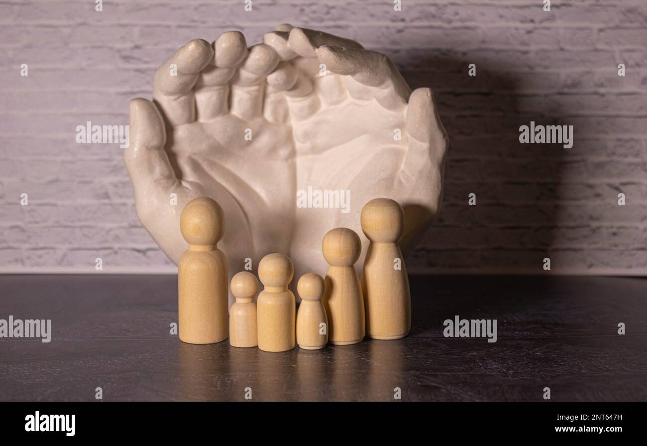 Figurines en bois d'une famille et une carte de crédit avec une flèche vers le bas à côté d'une maison blanche. Le concept de réduire un prêt immobilier à un jeune grand famil Banque D'Images