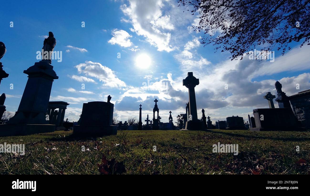 Ombragée silhouetait des graviers de cimetière et traverse un angle bas sur un ciel ensoleillé avec des nuages éclairés Banque D'Images