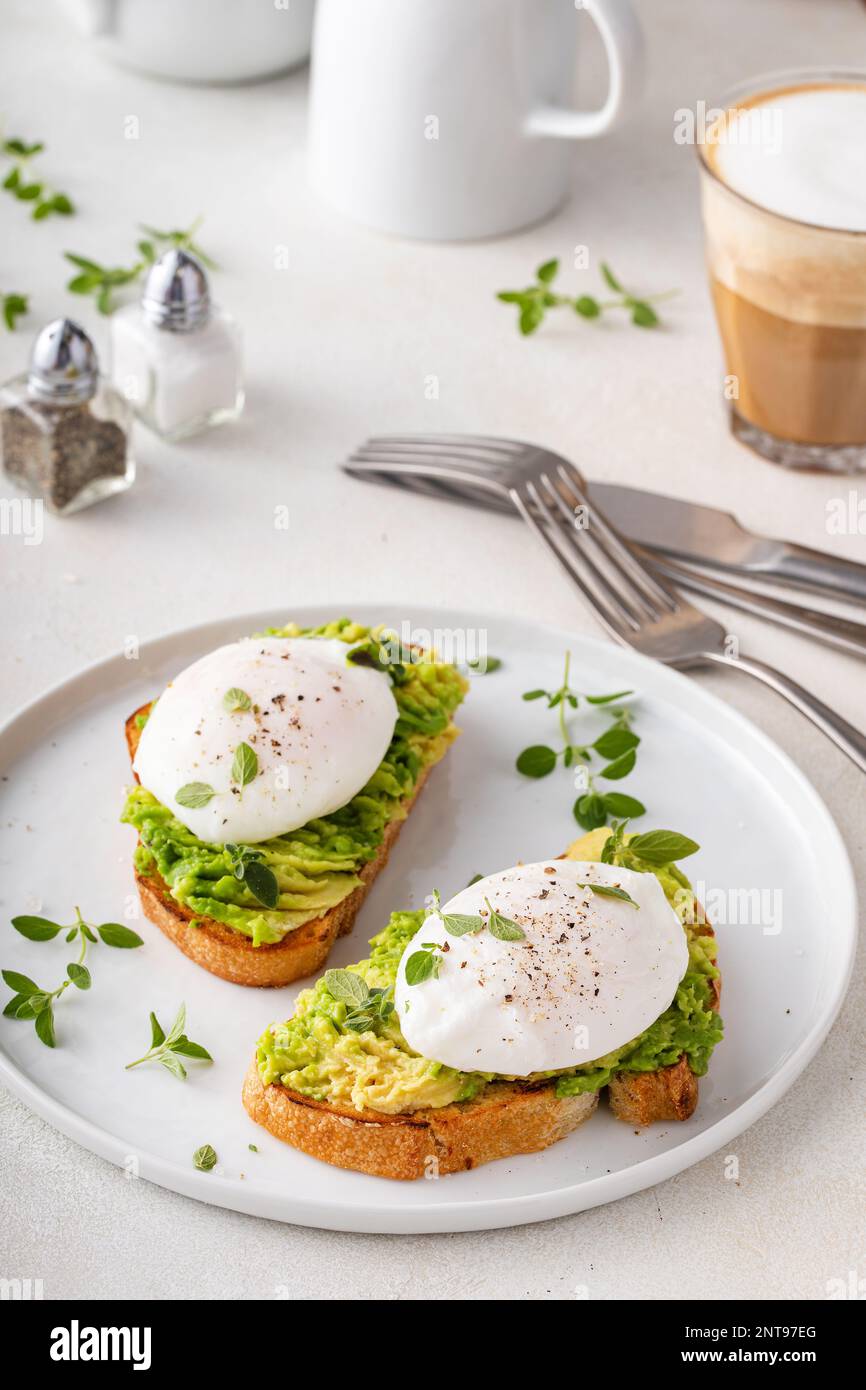 Pain grillé au levain avec purée d'avocat et œufs pochés aux herbes, idée de petit déjeuner sain Banque D'Images