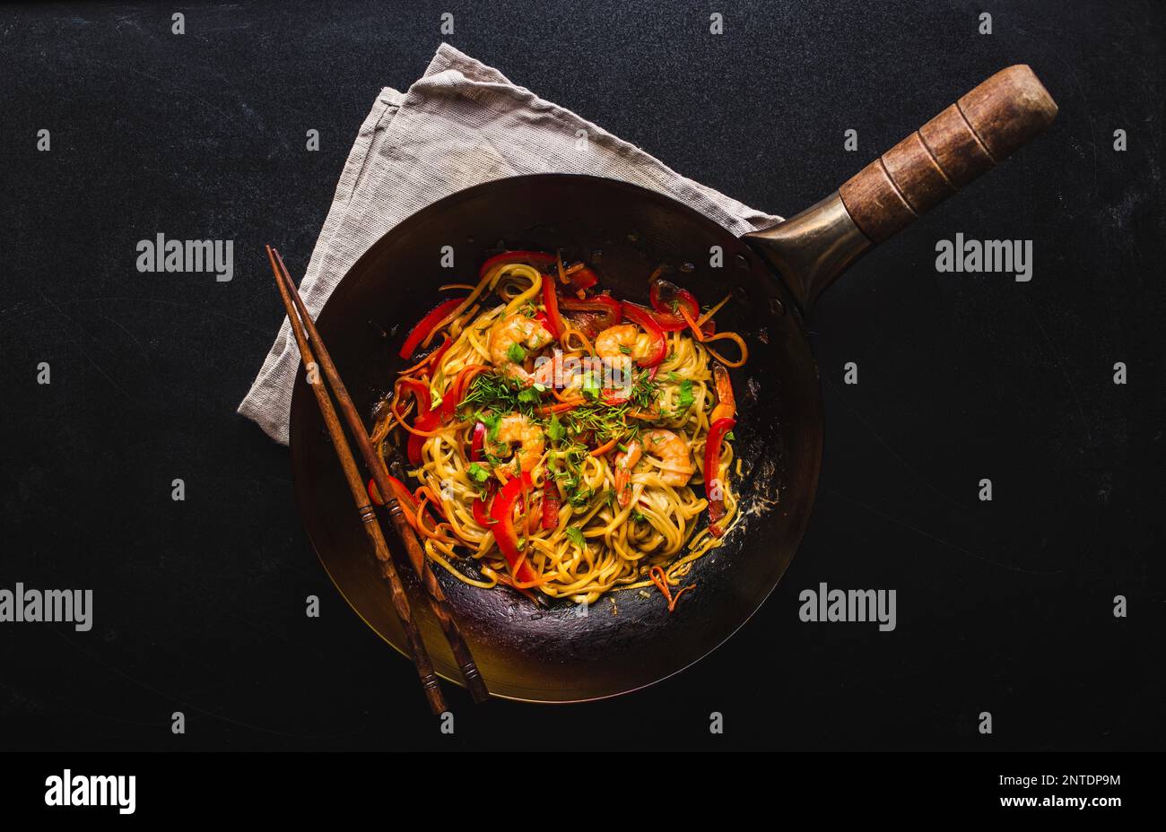 Remuez les nouilles dans le wok chinois traditionnel, les baguettes.  Nouilles asiatiques avec légumes, crevettes. Nouilles wok, dîner/déjeuner  chinois. Noir foncé Photo Stock - Alamy