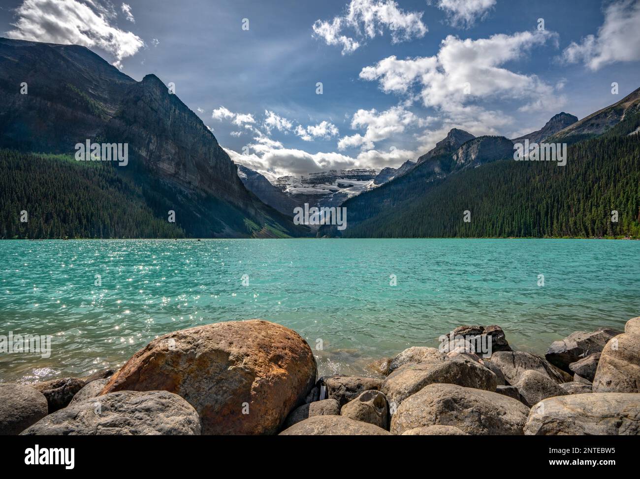 Vue imprenable sur le lac Louise avec vue sur le premier plan en pierre et le paysage rocheux des montagnes. Banque D'Images