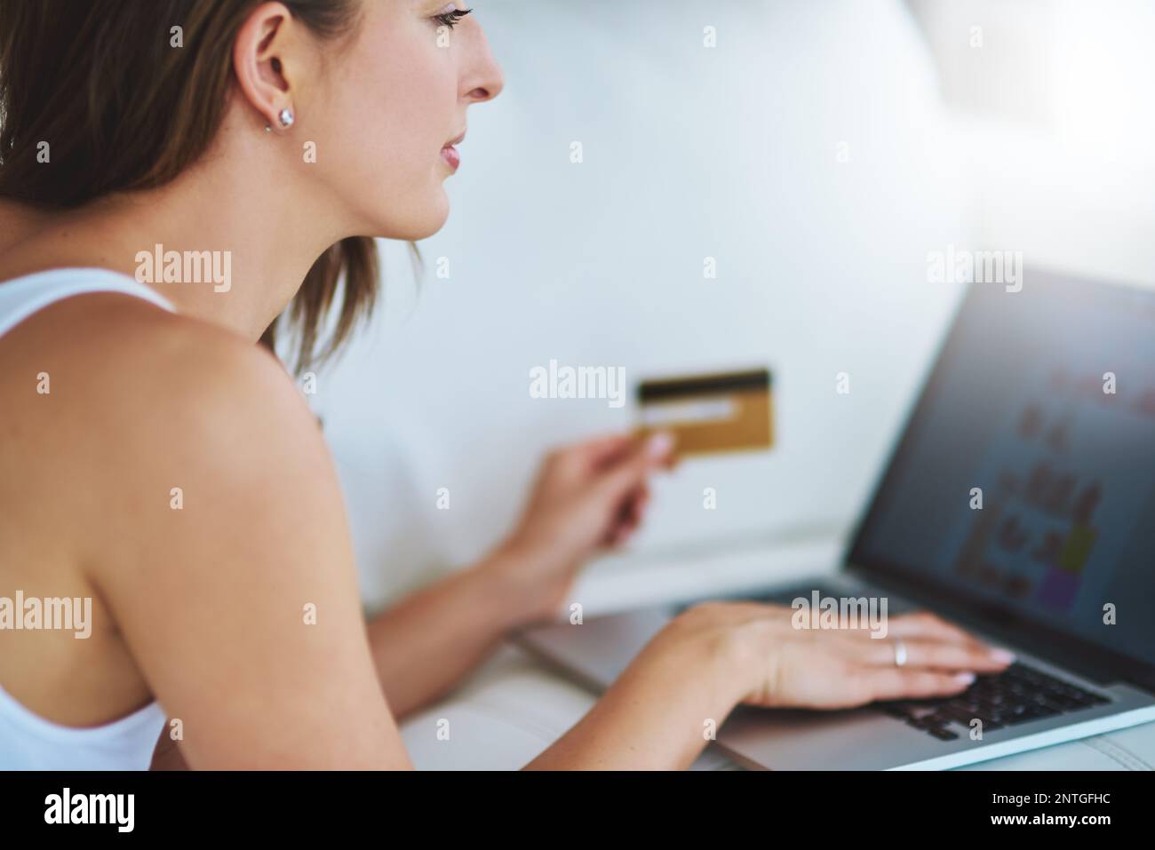 Le week-end, faites du shopping dans le confort de la maison. une jeune femme utilisant sa carte de crédit pour effectuer un paiement en ligne à la maison. Banque D'Images