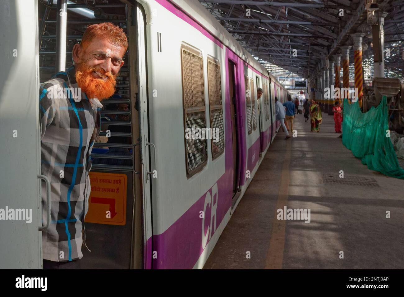 Un musulman avec une barbe de couleur henné se trouve à l'entrée d'un faux train de banlieue à Chhatrapati Shivaji Maharaj Terminus à Mumbai, en Inde Banque D'Images