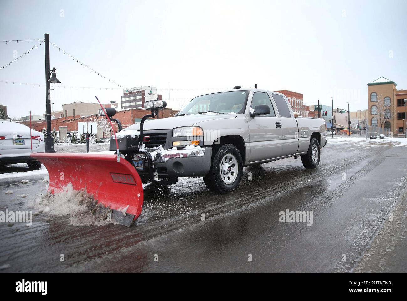 A truck plows a parking lot after initial snowfall and before a
