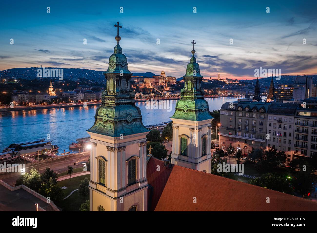 Budapest, Hongrie - vue aérienne de l'église mère de notre-Dame de l'Assomption illuminée de Budapest au crépuscule avec le château de Buda Palais Royal a Banque D'Images