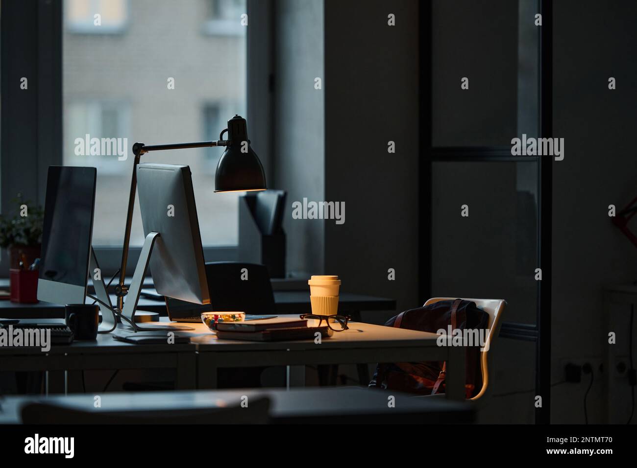 Image horizontale du lieu de travail du programmeur avec ordinateur sur table dans le bureau sombre Banque D'Images