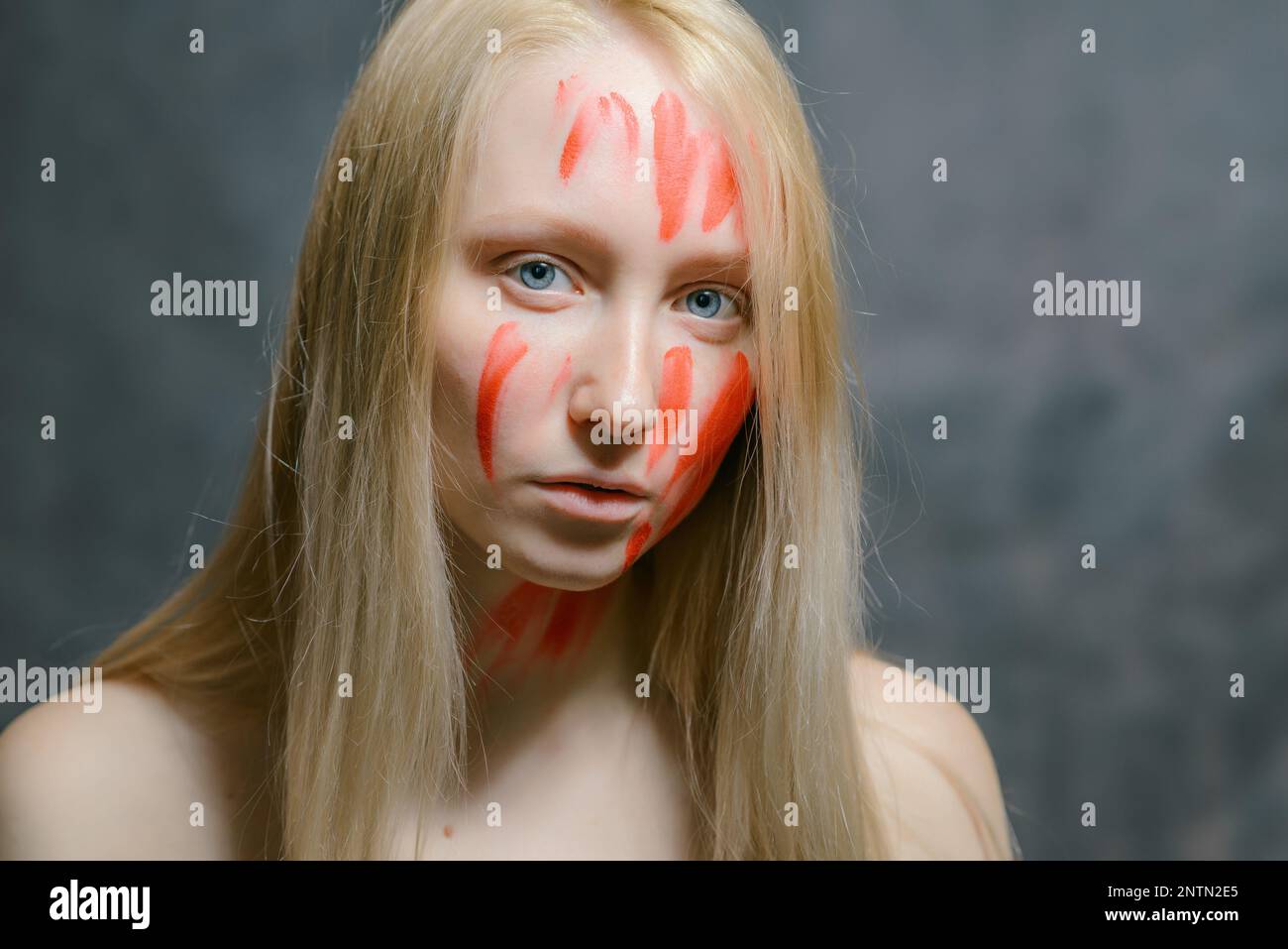 Portrait de jeune femme avec de la peinture sur son visage sur fond sombre. Banque D'Images
