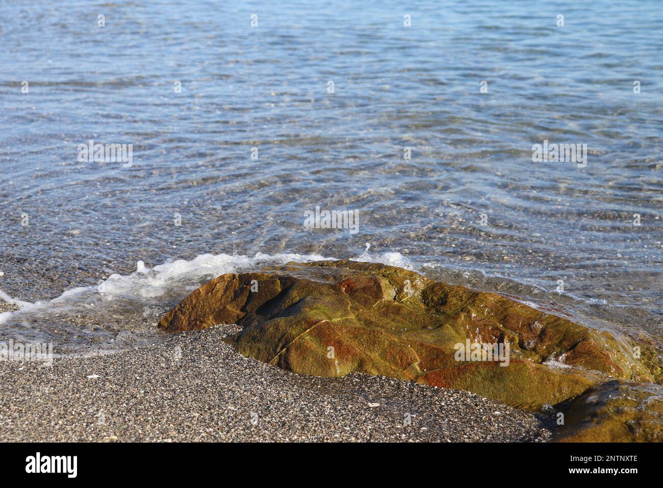 Un peu de vagues mousseuse qui frappent les Rocks sur la plage Banque D'Images