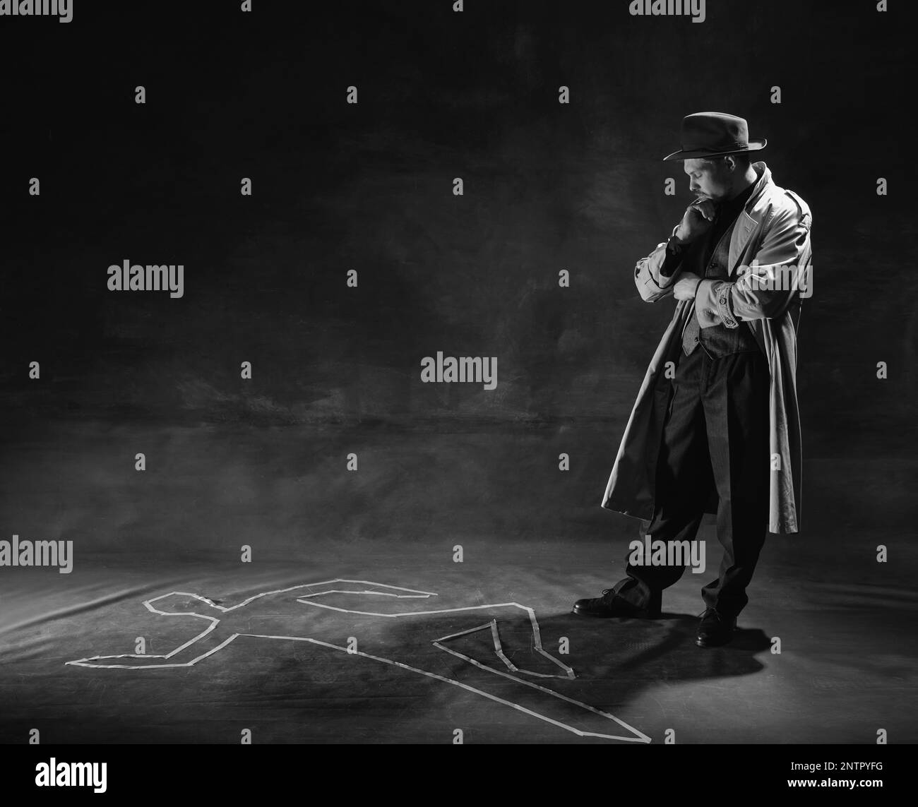 Noir et blanc, noir. Homme attentionné, détective en chapeau et trench-coat regardant sur la silhouette humaine dessinée sur le sol. Enquête sur le meurtre Banque D'Images