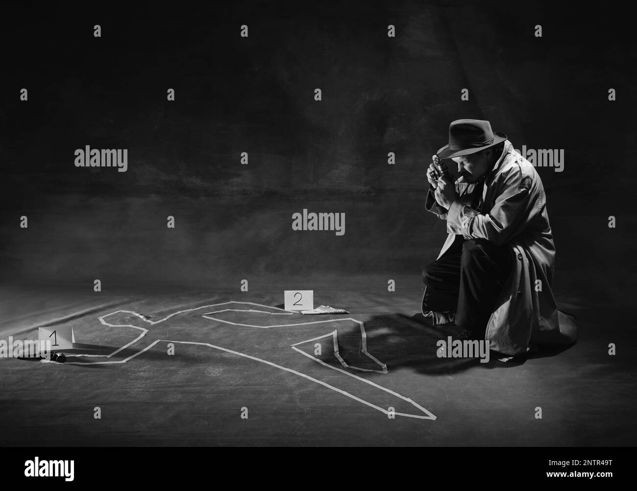 Noir et blanc, noir. Homme, détective en chapeau et trench-coat regardant la silhouette humaine dessinée sur le sol et faisant des photos de cas Banque D'Images