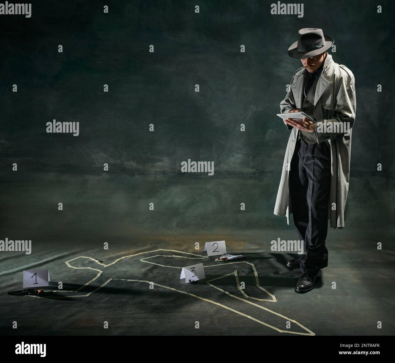 Portrait de l'homme, détective en trench-coat debout près de la silhouette humaine dessinée sur le sol et faisant des notes de cas sur fond vert foncé vintage Banque D'Images