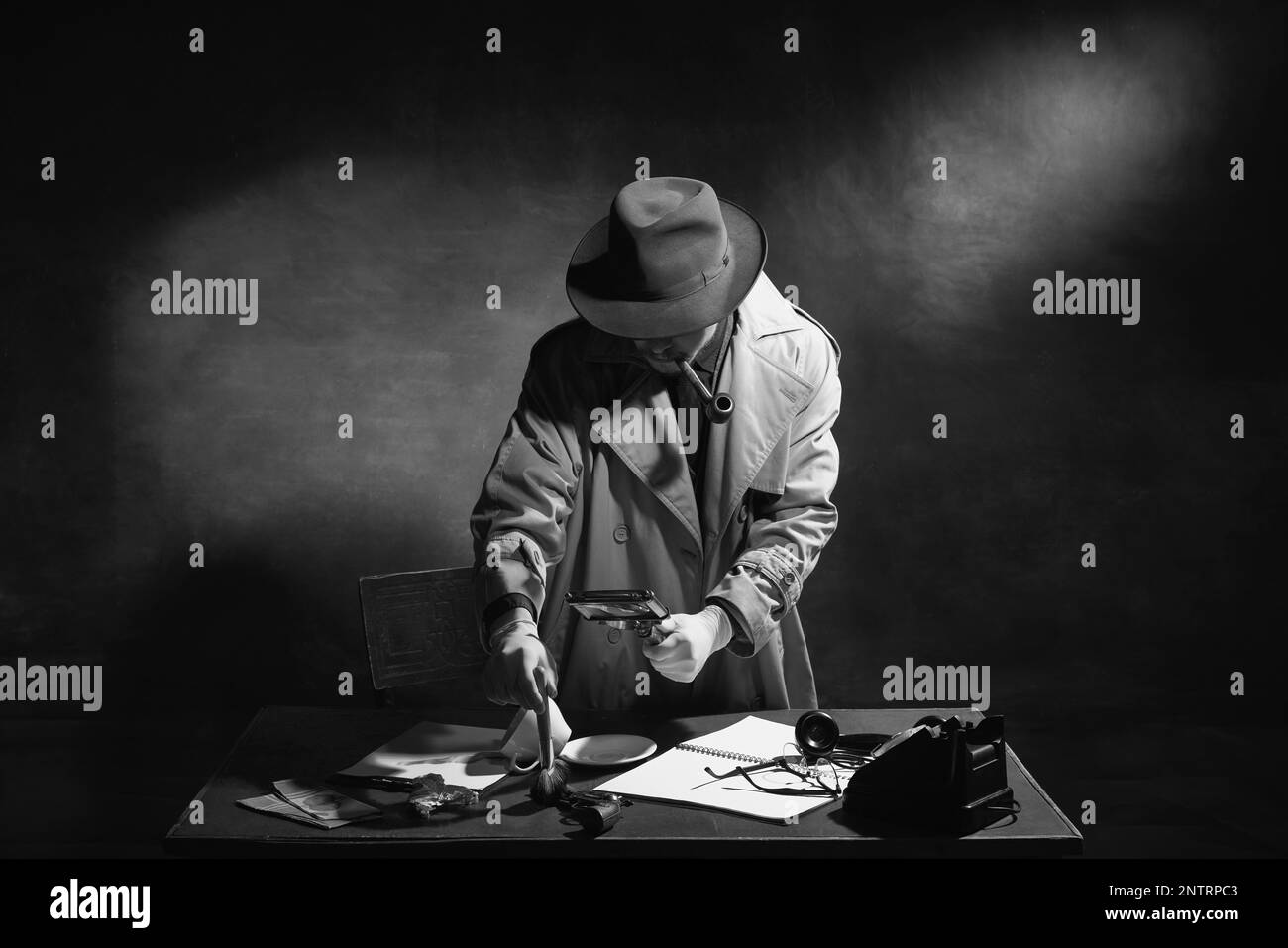 Noir et blanc, noir. Homme, détective professionnel dans le chapeau, fumer pipe et regarder sur indice, trouver des empreintes digitales Banque D'Images