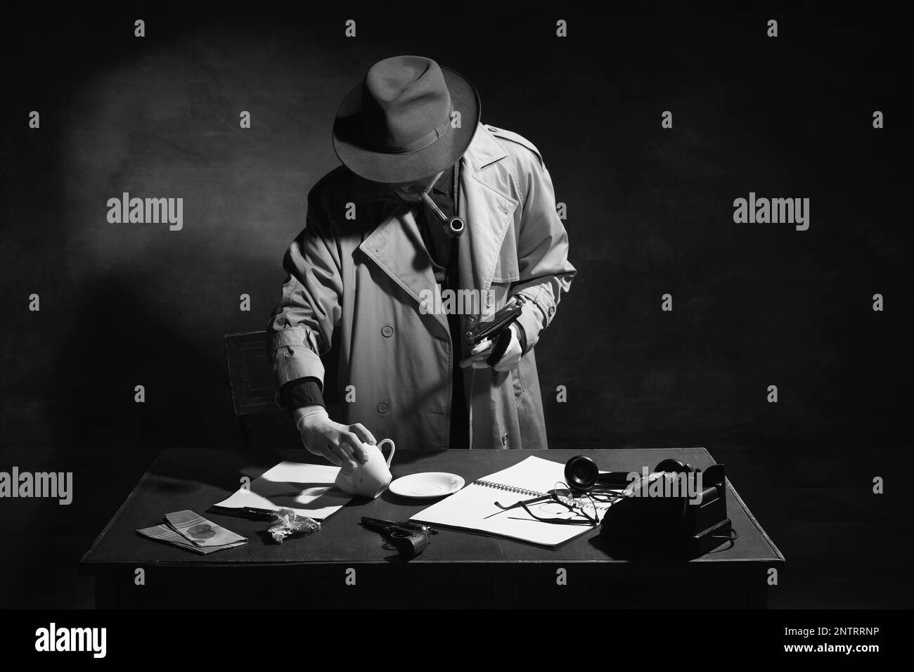 Noir et blanc, noir. Homme, détective professionnel, inspecteur en trench-coat regardant à travers des indices de cas, tasse, mouchoir Banque D'Images