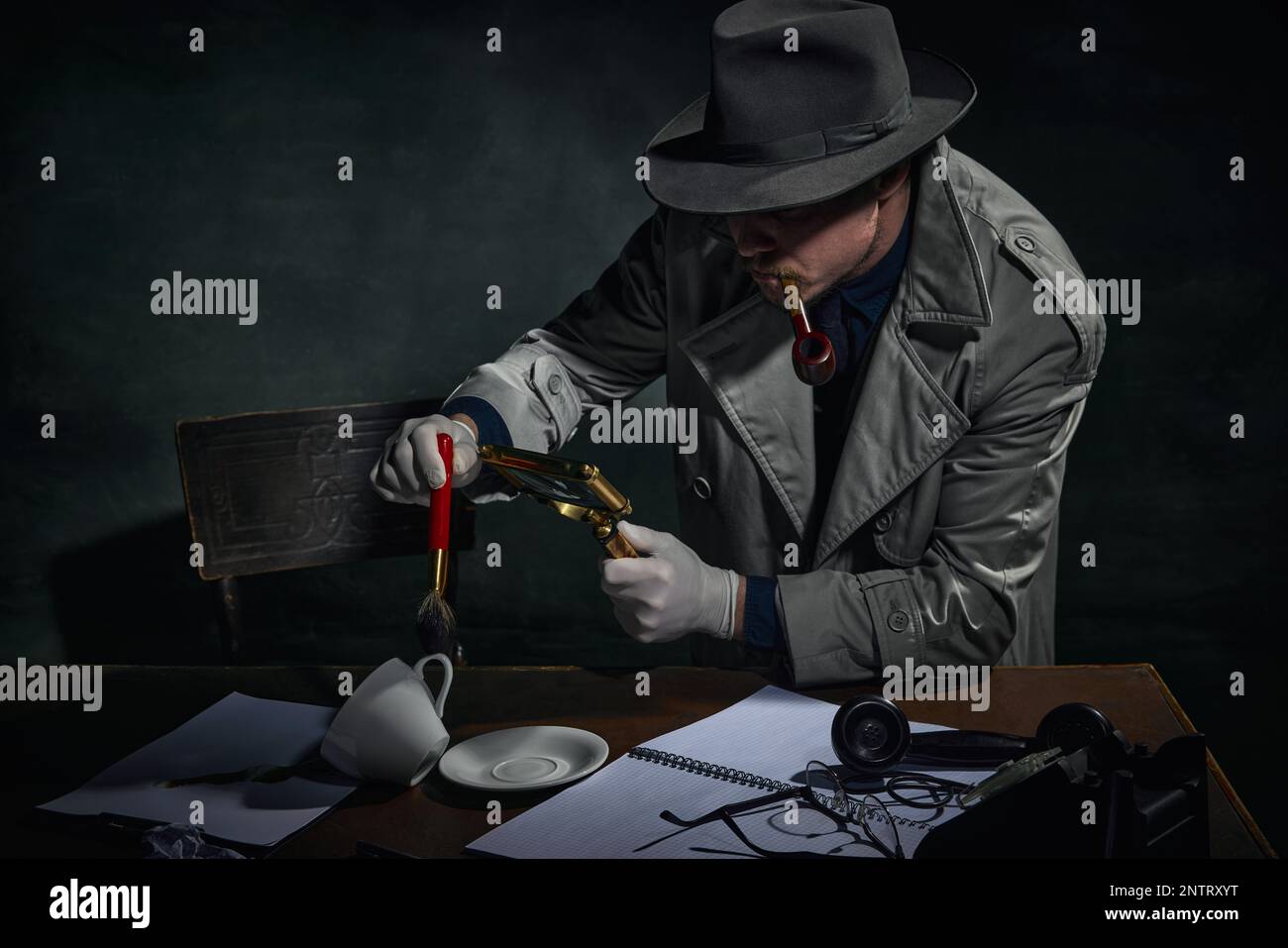 Détective professionnel en trench coat trouvant des empreintes digitales sur des indices de cas sur fond vert foncé vintage. Enquête Banque D'Images