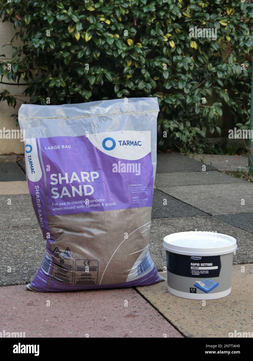 Sac de sable pointu et ciment à séchage rapide sur dalles de pavage, Royaume-Uni Banque D'Images