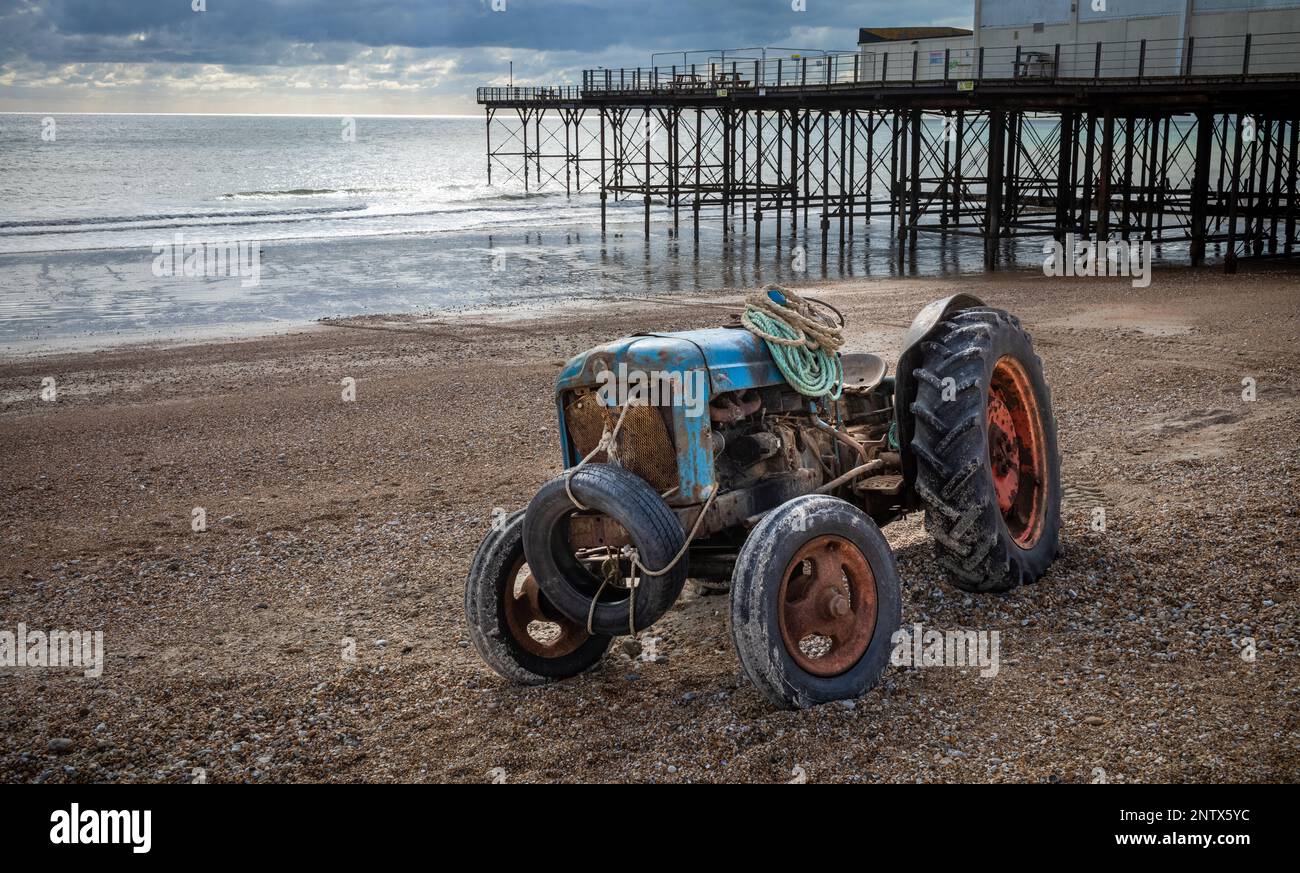 Un tracteur vintage et rouillé utilisé par un pêcheur pour amener son bateau, se trouve stationné sur la plage de galets, devant le quai de Bognor Regis, dans l'ouest du Sussex, Banque D'Images