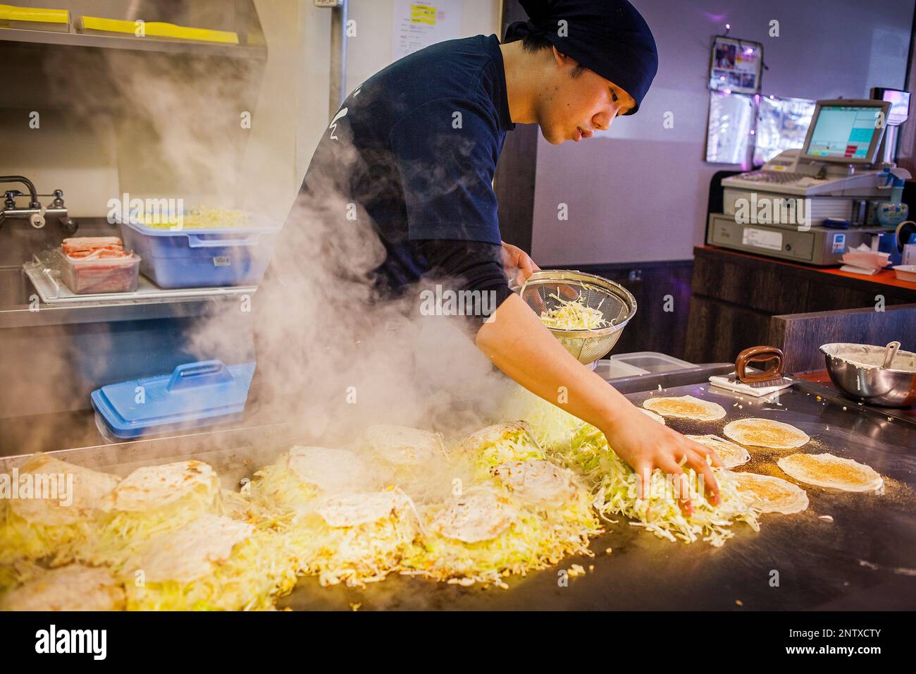 Okonomiyaki, chef au restaurant de l'okonomi-mura, Hiroshima, Japon Banque D'Images