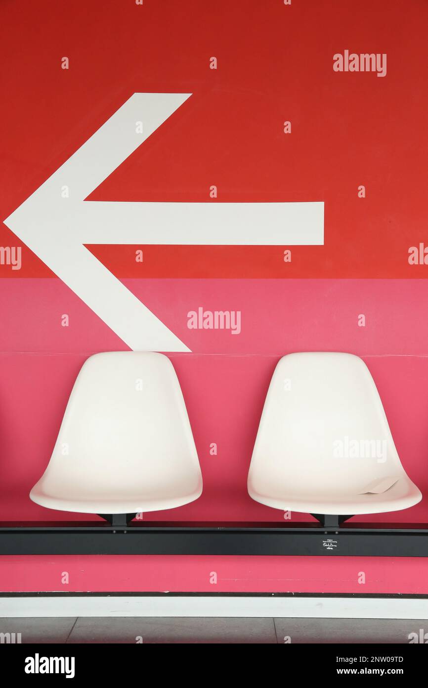 Flèche directionnelle blanche sur le mur rouge dans la salle d'attente d'un salon Banque D'Images