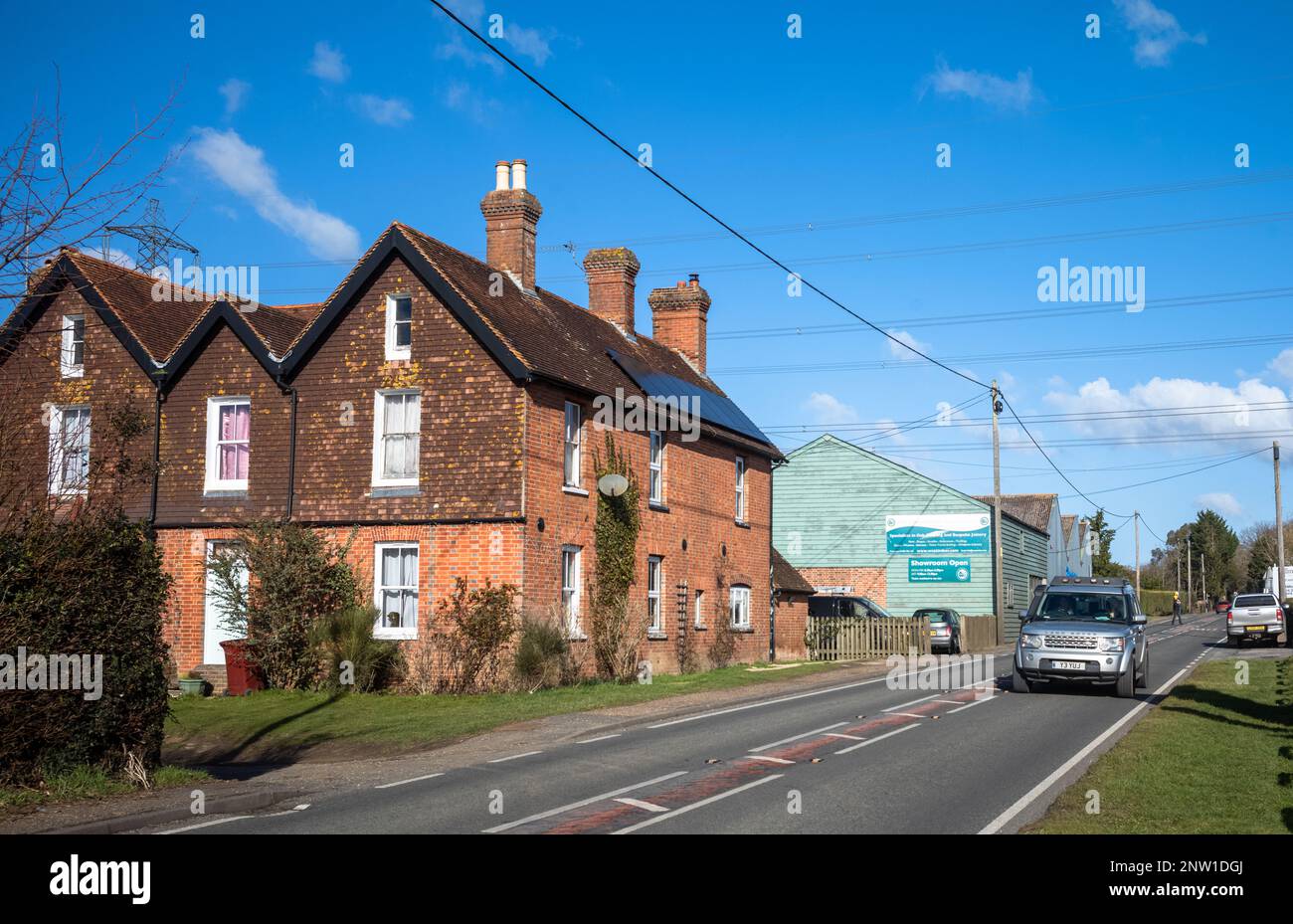 Une voiture Land Rover Discovery passe devant des cottages anciens sur une route de campagne à Wisborough Green, au Royaume-Uni. Banque D'Images