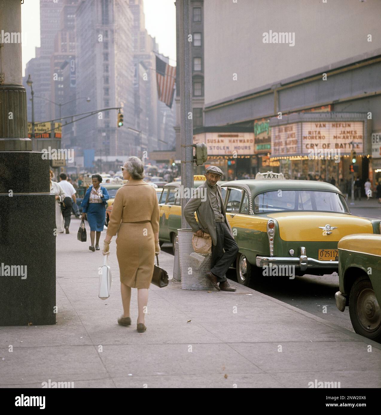 États-Unis New York 1964. Une scène de rue avec des voitures, des bus et des taxis en voiture sur Broadway dans le quartier de Times Square sur Manhattan. Les salles de cinéma affichent des heures de vol et un cri de bataille, tous deux créés aux États-Unis en octobre-novembre 1963. Devant une femme marchant sur le trottoir avec un homme avec un sac en papier dans sa main, habituellement un signe qu'il contient une sorte d'alcool. Crédit Roland Palm réf. 5-39-4 Banque D'Images