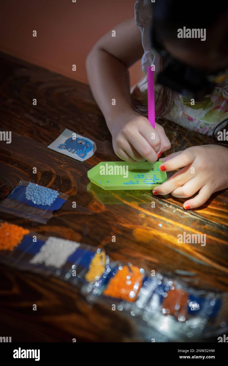 Une jeune fille crée l'art avec ses propres mains en collant des pierres. Banque D'Images