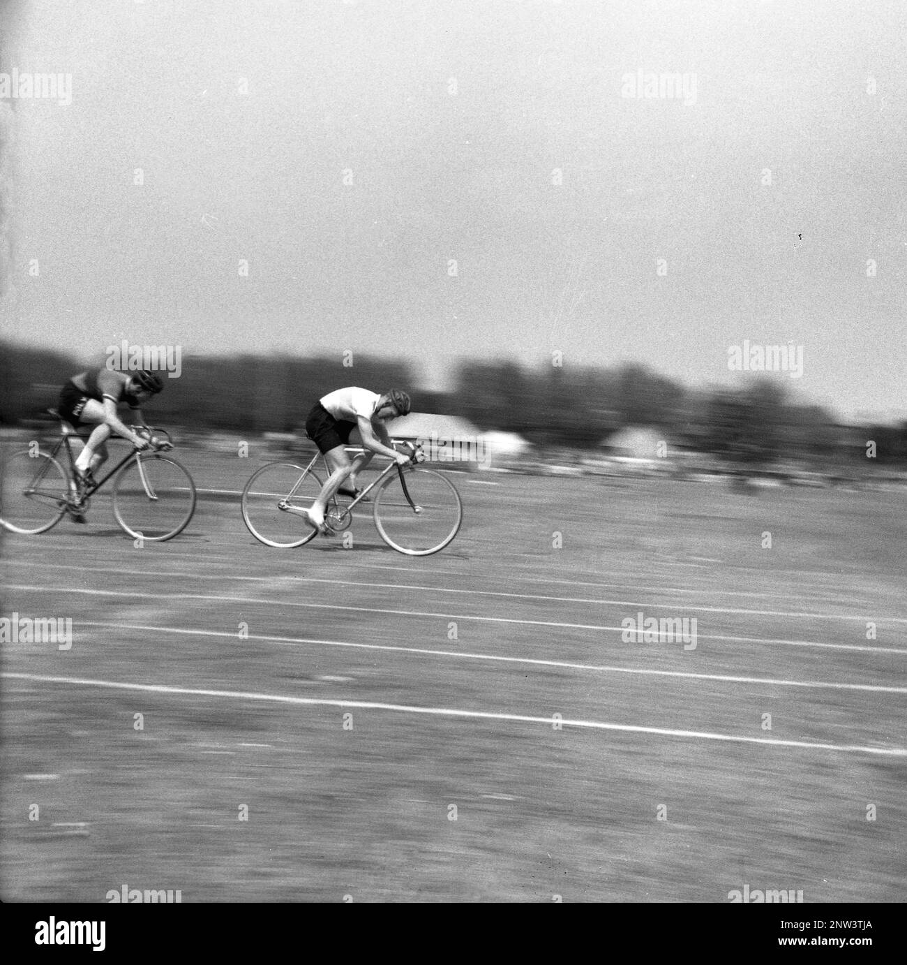 1950s, historique, deux hommes concurrents prenant part à la course de sprint cycle sur une piste d'herbe, Angleterre, Royaume-Uni. La course sur piste de gazon était une activité populaire en Grande-Bretagne à son époque, en particulier lors d'un lundi de Pentecôte, un jour férié ou un jour férié à la fin du mois de mai. Banque D'Images