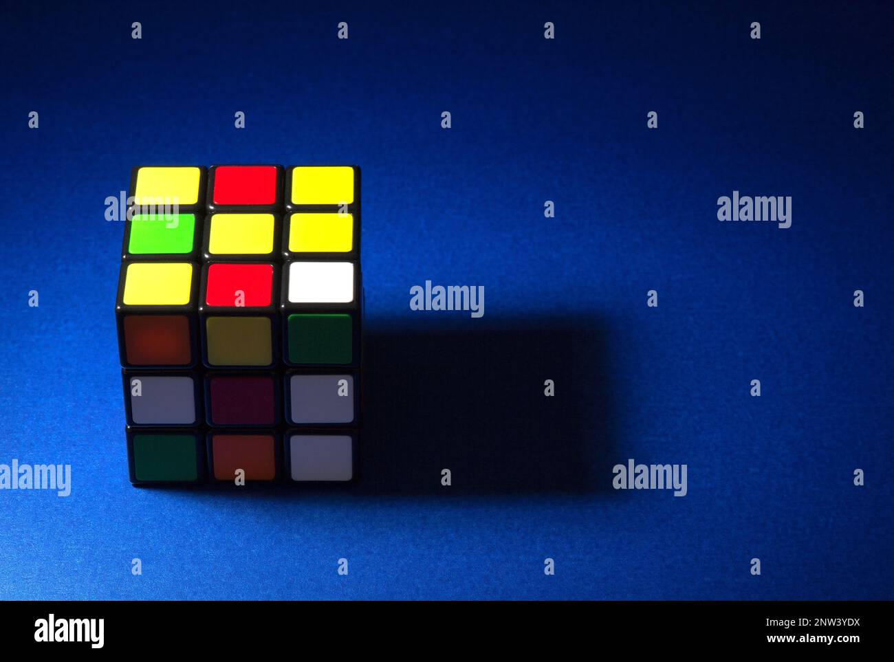 Cube de puzzle partiellement éclairé sur un plateau de table bleu Banque D'Images