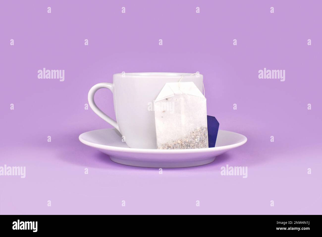 Tasse à thé avec sac de thé aux herbes sur fond violet Banque D'Images