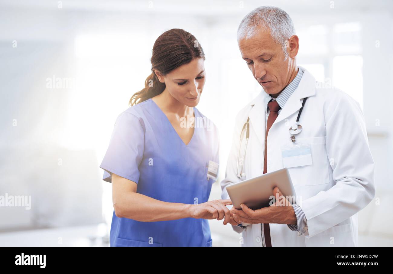 Comparaison des dossiers médicaux. Photo de deux professionnels de la santé regardant une tablette numérique. Banque D'Images