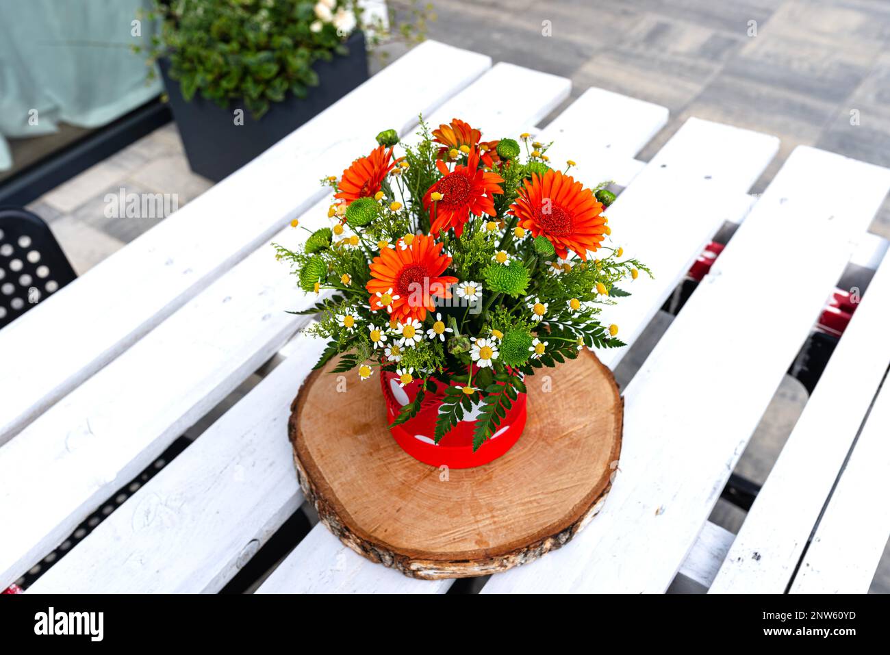 Un bouquet de gerbera et de fleurs sauvages de camomille dans un pot sur une table en bois blanc avec une palette. Banque D'Images