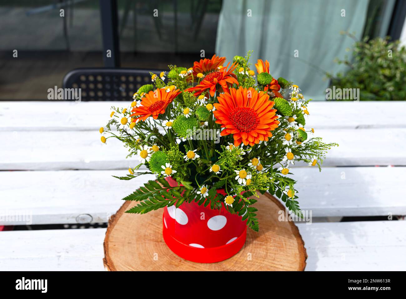 Un bouquet de gerbera et de fleurs sauvages de camomille dans un pot sur une table en bois blanc avec une palette. Banque D'Images