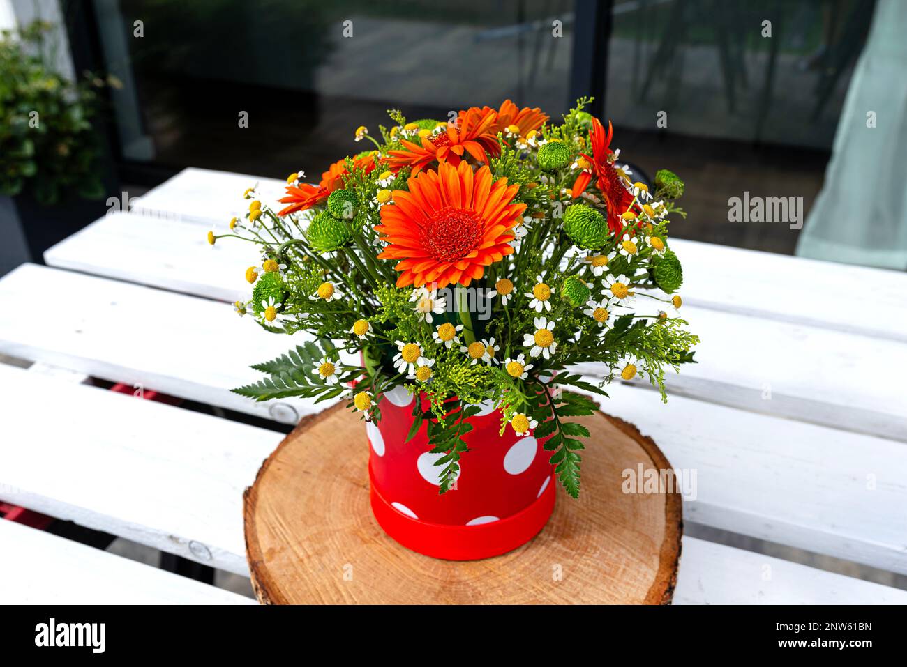 Un bouquet de gerbera et de fleurs sauvages de camomille dans un pot sur une table en bois blanc avec une palette. Banque D'Images