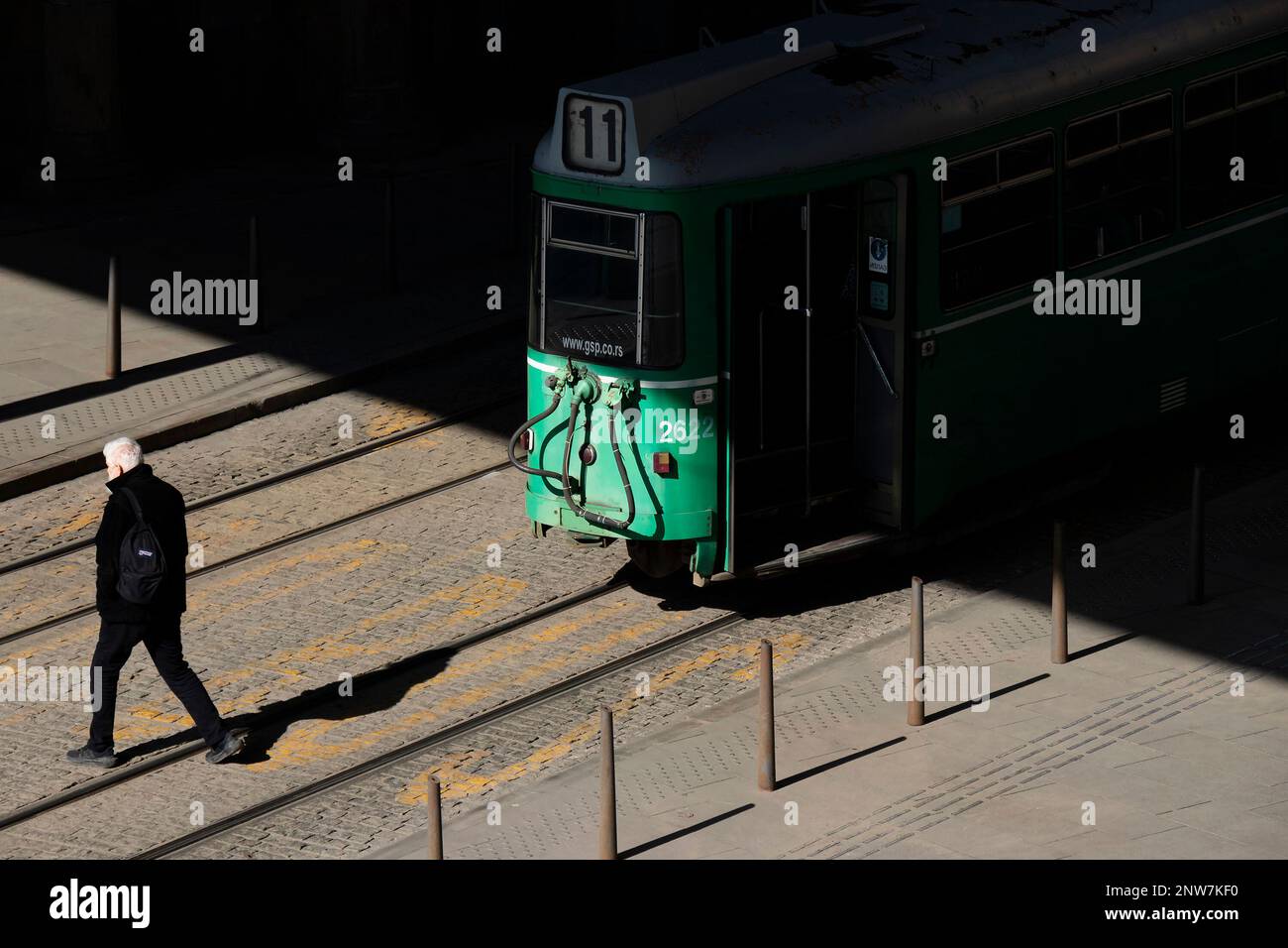 Belgrade, Serbie - 23 février 2023 : tramway vert numéro 11 se trouvant à l'arrêt de bus, et une personne traversant une route derrière elle, vue arrière à angle élevé Banque D'Images