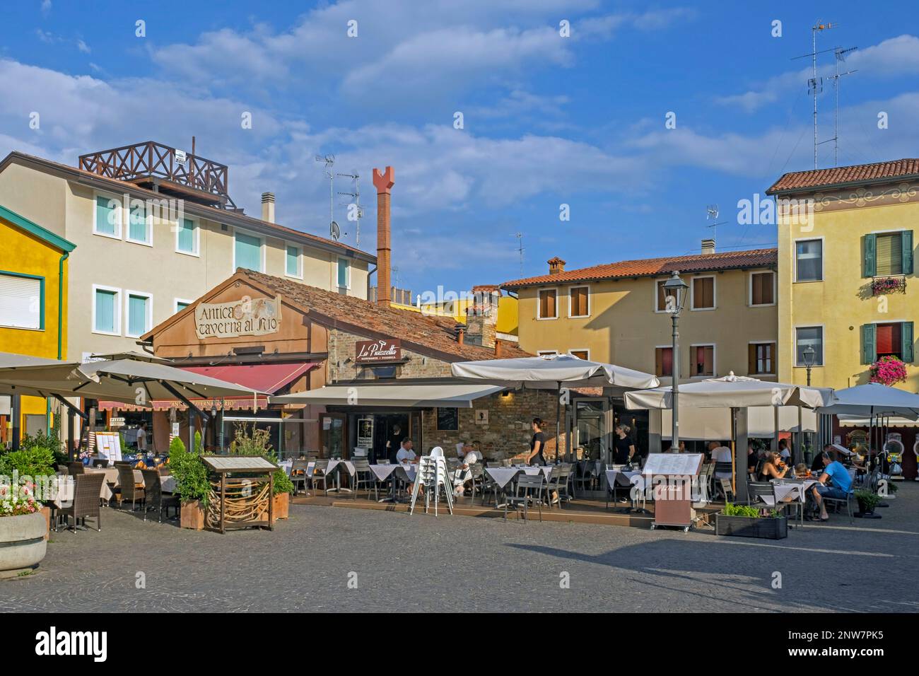 Touristes dans les restaurants dans le centre historique de Caorle, ville côtière dans la ville métropolitaine de Venise, Vénétie, Italie du Nord Banque D'Images