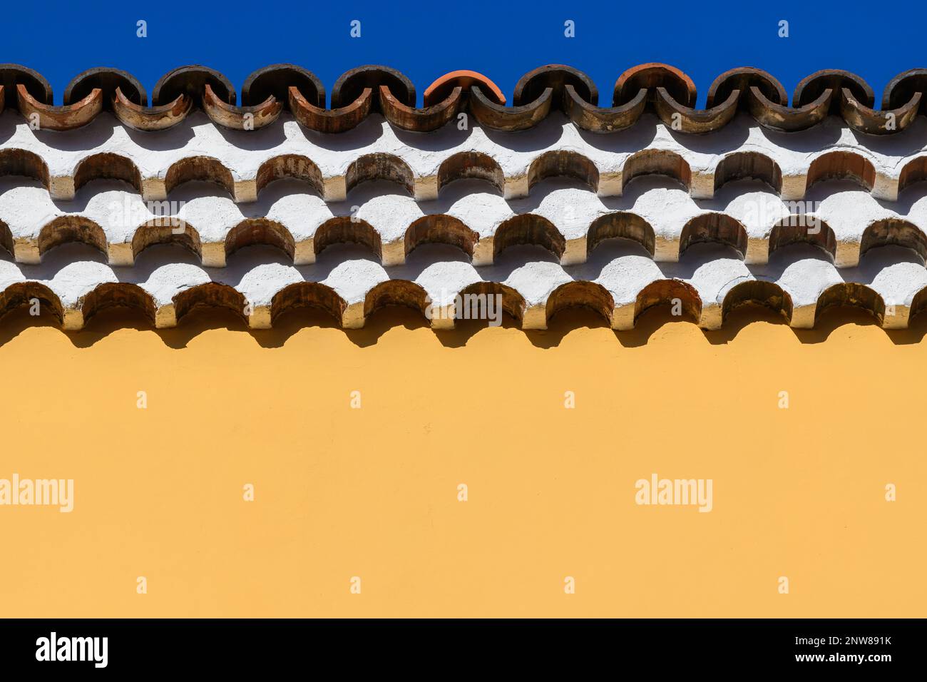 Des rangées complexes de gouttières génoise blanchies à la chaux contrastent avec un mur en stuc jaune vif sur un bâtiment à San Cristobal de la Laguna à Tenerife Banque D'Images