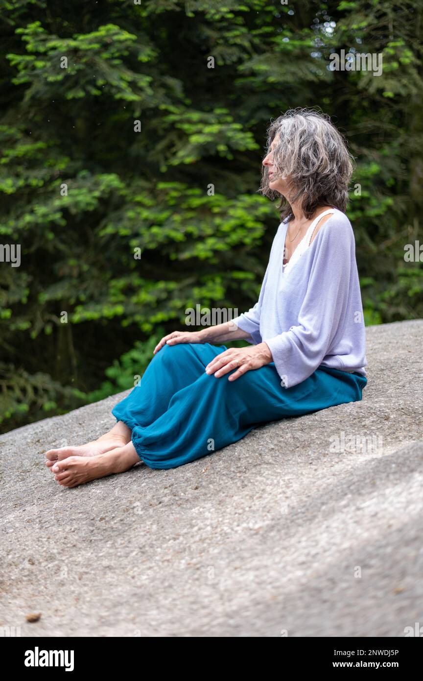 Femme en ligne méditation assise sur un énorme rocher de granit Banque D'Images