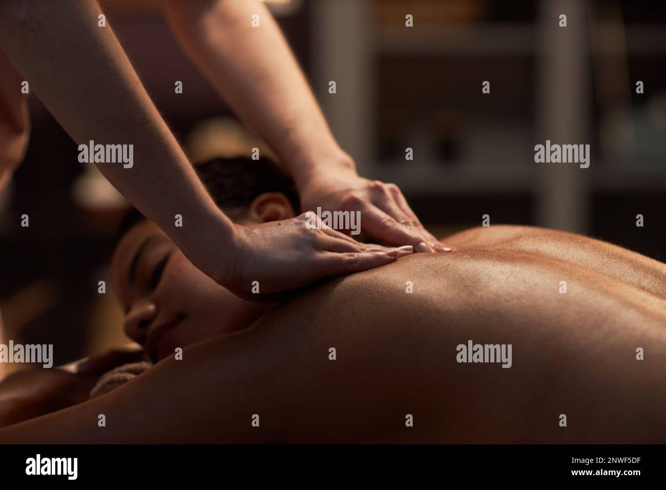 Thérapeute appliquant une pression profonde lors du massage du dos de la jeune femme Banque D'Images