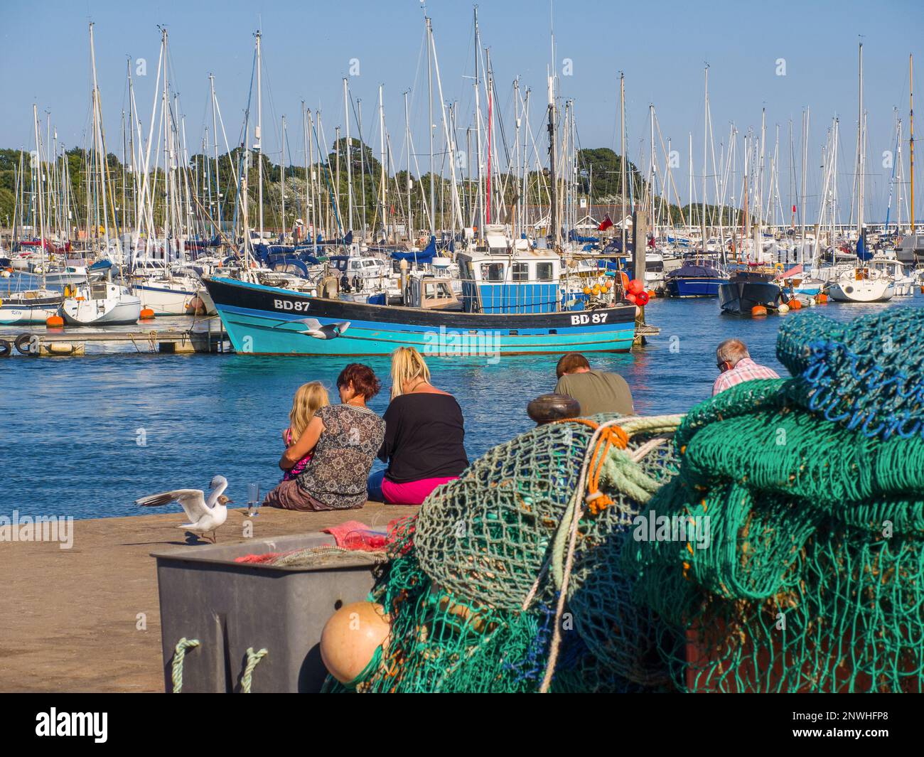 Famille assise sur le quai au port et à la marina de Lymington Banque D'Images