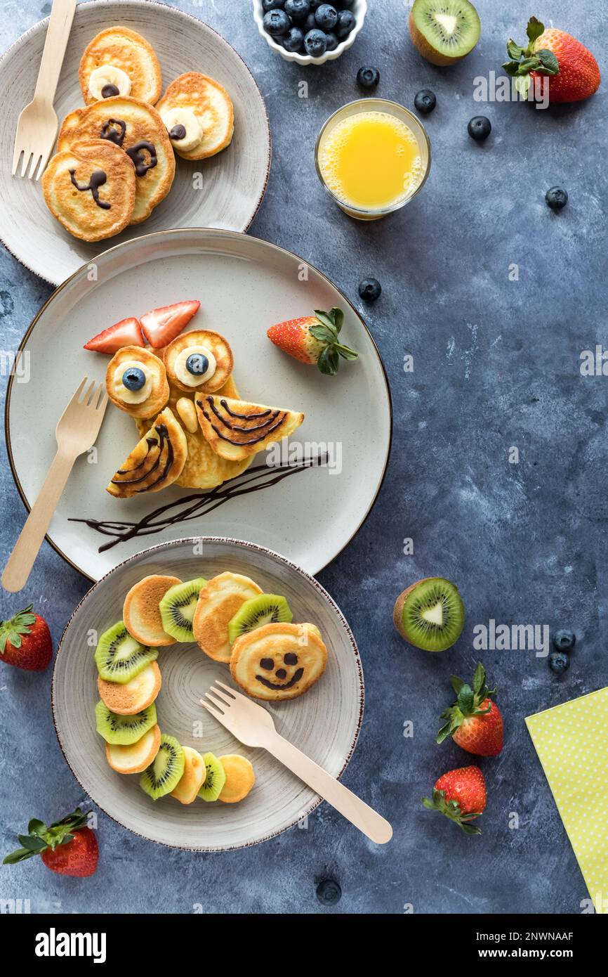 Crêpes aux formes de créatures, servies avec des fruits et du jus pour les enfants. Banque D'Images
