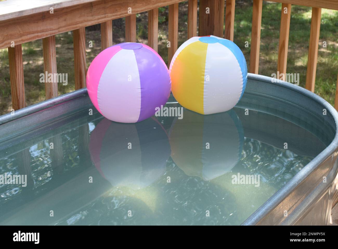 Deux ballons de plage gonflés flottant dans un réservoir de stockage. Un endroit rafraîchissant pour se rafraîchir par une chaude journée d'été. Banque D'Images