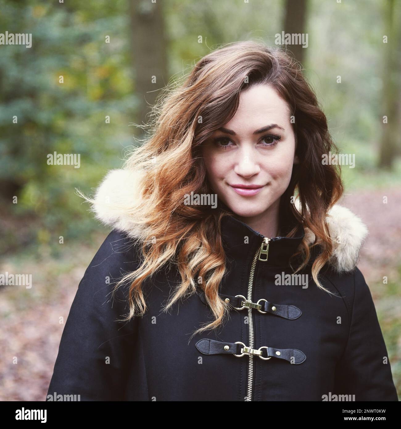 Portrait de plein air d'une jeune femme en contact avec la nature, le port de manteau d'hiver en forêt sur une froide journée d'automne Banque D'Images