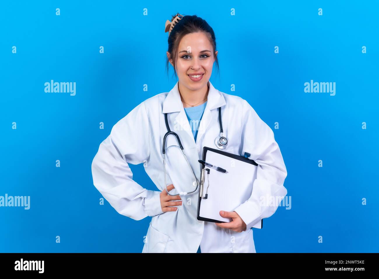 Portrait de femme souriante médecin en robe médicale debout isolée sur bleu, concept de médecine Banque D'Images