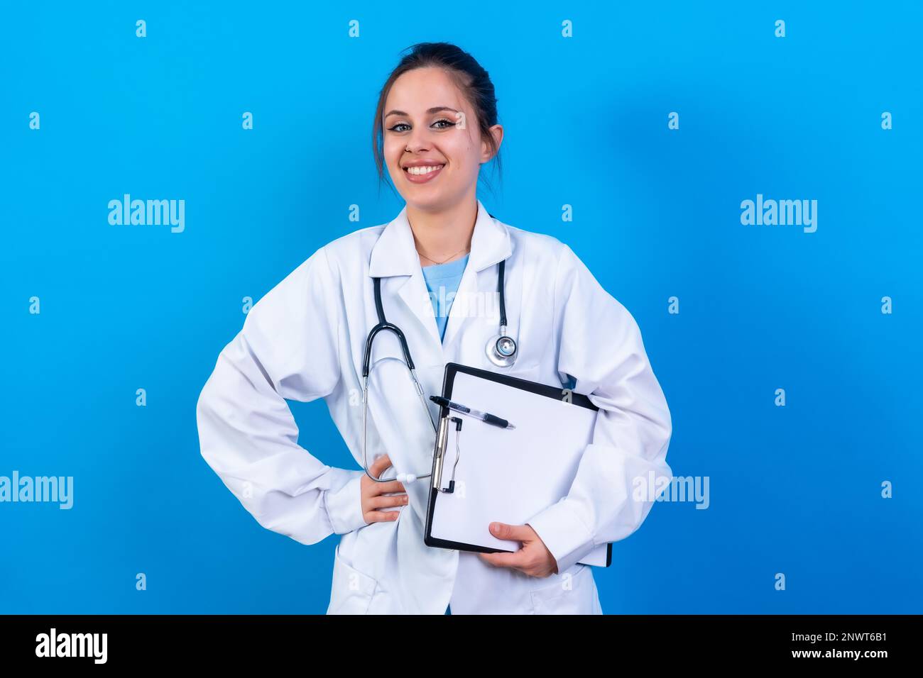 Portrait de femme souriante médecin en robe médicale debout isolée sur bleu, concept de médecine Banque D'Images