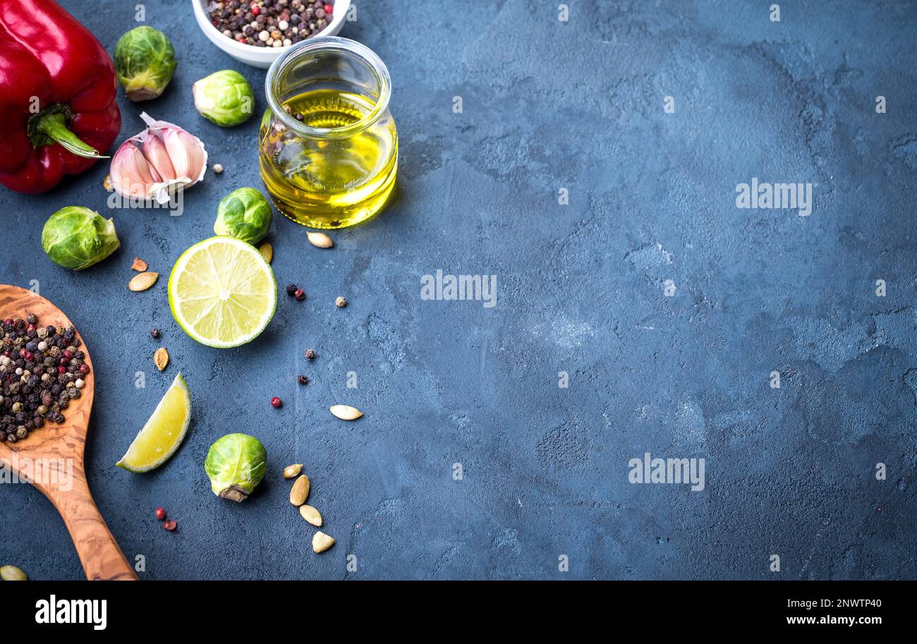 Ingrédients pour la cuisson. Huile d'olive dans un pot en verre, cuillère de cuisson en bois, épices, poivron rouge, lime, bruxelles sprout, ail, assaisonnements colorés. Banque D'Images