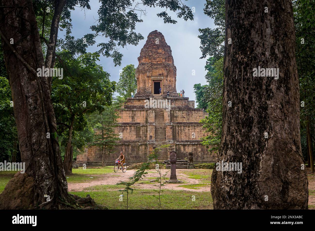 Femme vélo, temple de Baksei Chamkrong, Parc archéologique d'Angkor, Siem Reap, Cambodge Banque D'Images