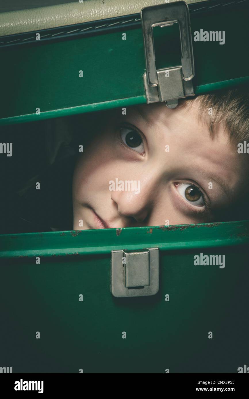 l'enfant se cache dans une vieille valise verte, portrait en gros plan Banque D'Images