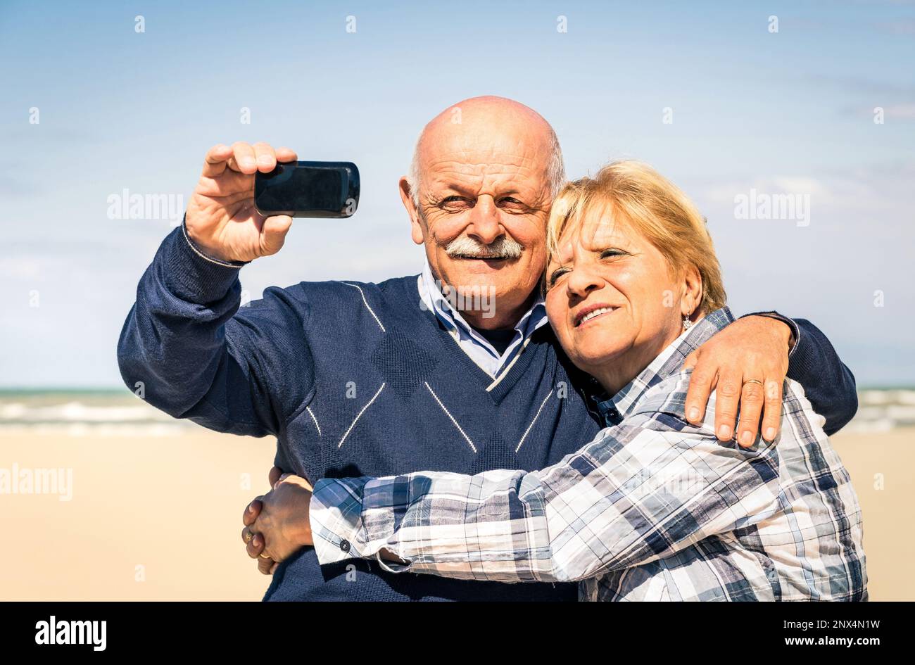 Couple heureux senior prenant un selfie à la plage pendant le printemps en attendant l'été - concept de personnes âgées et interaction avec les nouvelles technologies et t Banque D'Images