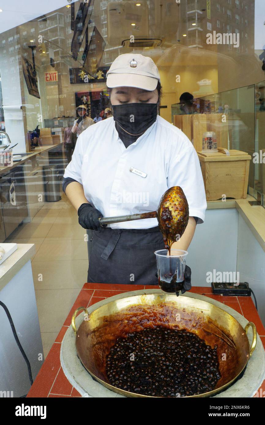 Un jeune américain asiatique prend un verre de lait boba dans la fenêtre de Xing Fu Tang, un magasin taïwanais sur Main St. à Flushing, Queens, quartier chinois de New York. Banque D'Images