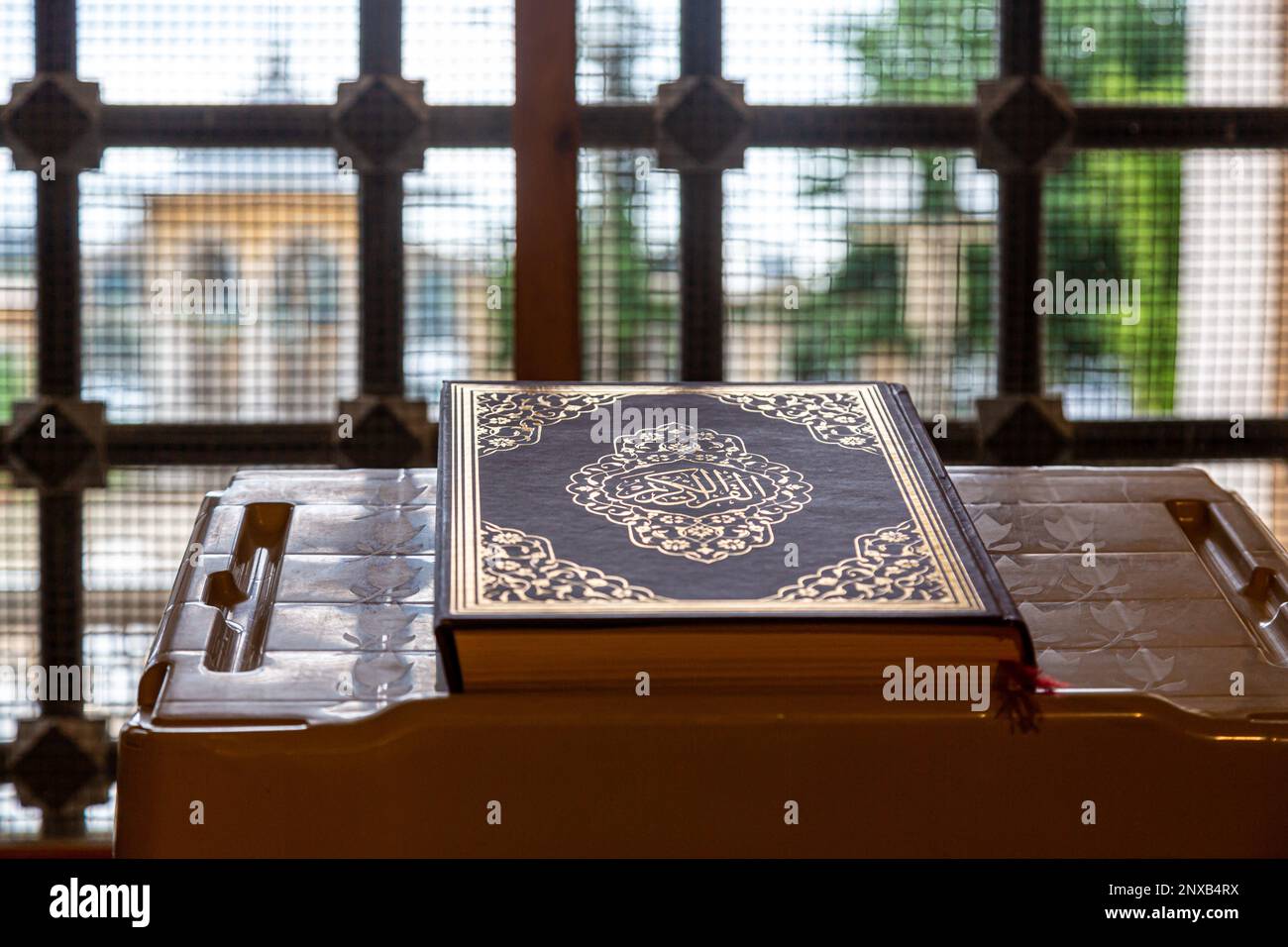 Le livre Saint des musulmans, le Coran (Kur'an-ı Kerim), sur la table de lecture par la fenêtre barrée, en vue sélective. Banque D'Images